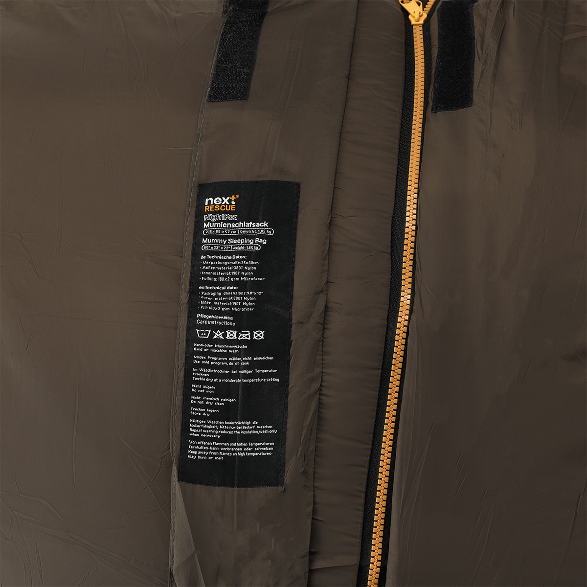 Nahaufnahme eines braunen taktischen Mumienschlafsacks von nextRESCUE mit dem Produktetikett mit technischen Spezifikationen.