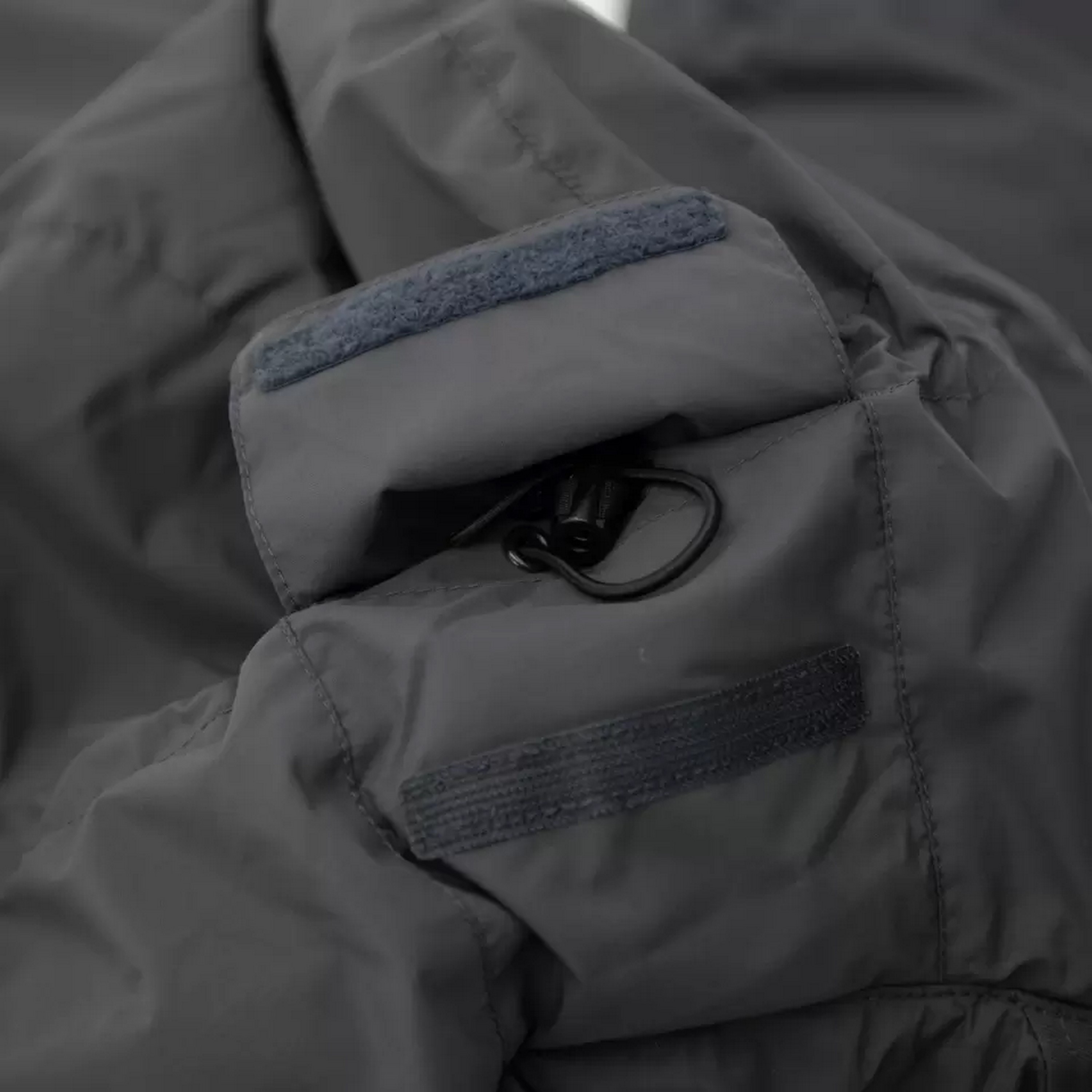 Nahaufnahme einer dunkelgrauen taktischen Jackentasche mit sicherem Klettverschluss und verstellbarem Kordelverschluss.