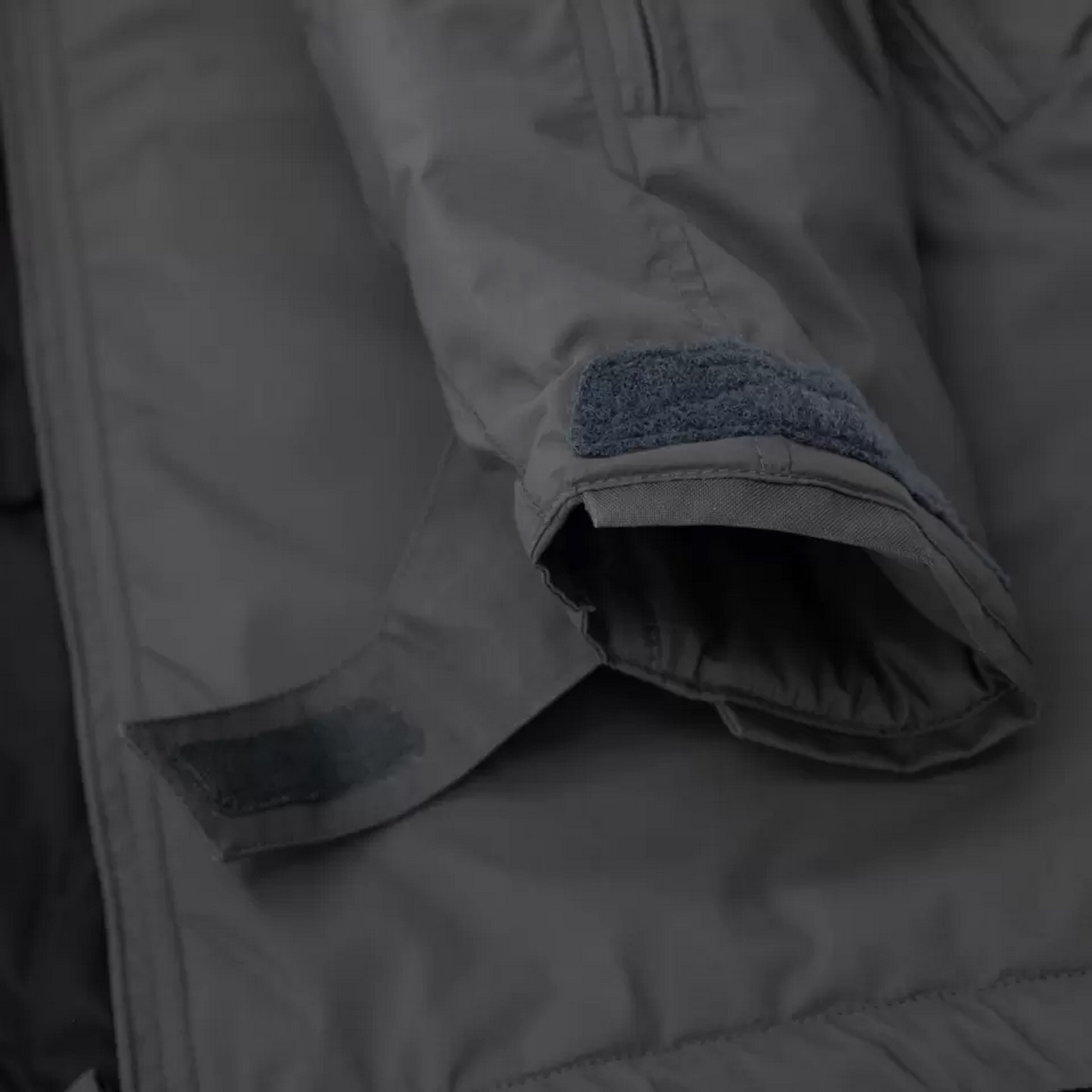 Nahaufnahme eines grauen taktischen Jackenärmels mit verstellbarem Klettverschluss für eine sichere, professionelle Passform.