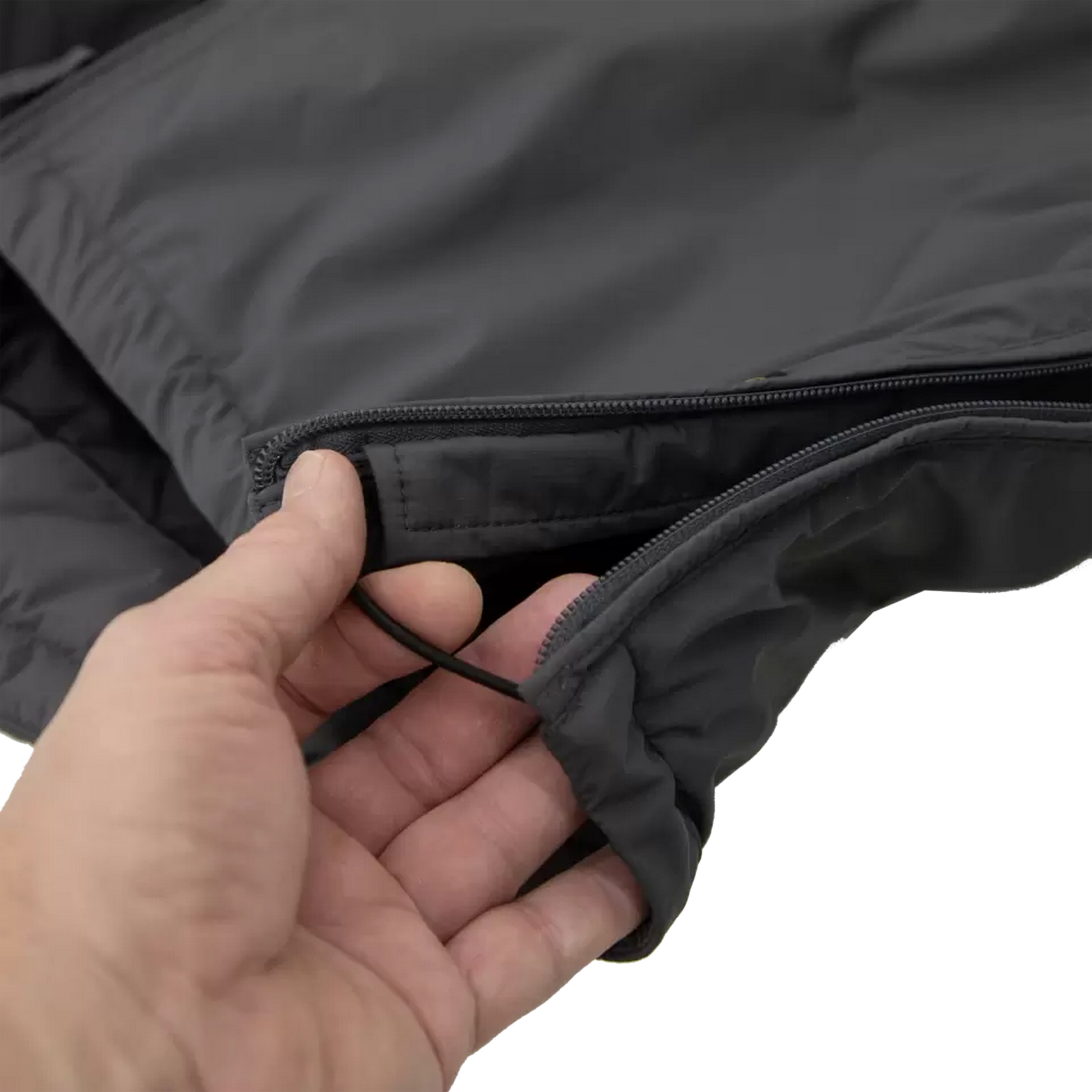 Nahaufnahme einer Hand, die den robusten Reißverschluss einer dunkelgrauen Einsatzjacke öffnet, die für den Notfall und den Feldeinsatz konzipiert ist.